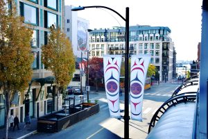 Downtown Victoria street scene featuring colorful Indigenous art banners hanging from light poles