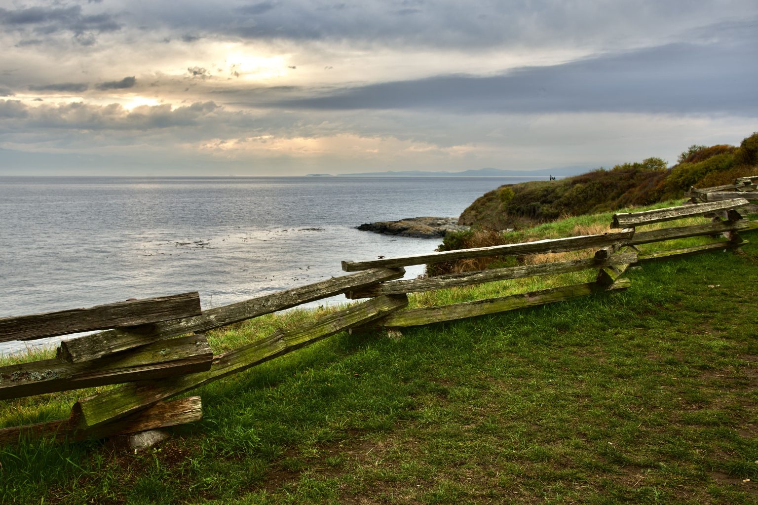 Wooden split-rail fence along the grassy Dallas Road waterfront trail in Victoria overlooking the ocean